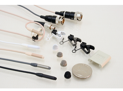 This is a photo of all four colours of the Sanken COS-11D R/RM microphone. Black, grey, white and beige. In the picture it's shown with two connectors as well. Also shown with accessories including microphone clips and microphone wind protectors